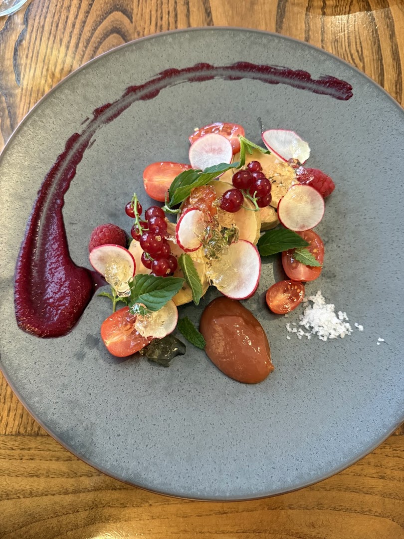 Une assiette composée de tomates, baies rouges, radis et jeunes feuilles